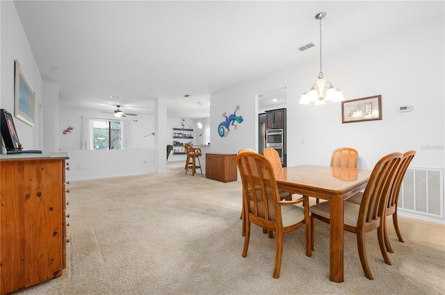 dining space with ceiling fan with notable chandelier and light colored carpet