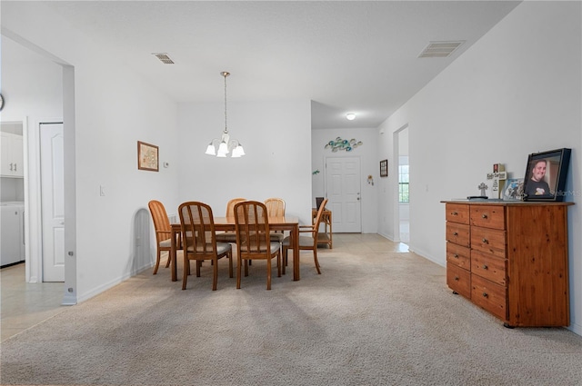 dining area with an inviting chandelier, washer / clothes dryer, and light colored carpet