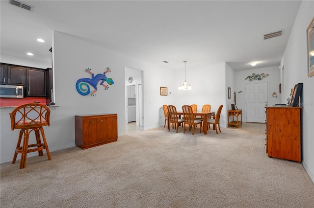 carpeted dining area with a chandelier