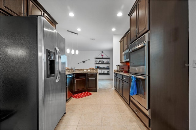 kitchen with hanging light fixtures, stainless steel appliances, light stone counters, dark brown cabinetry, and light tile flooring