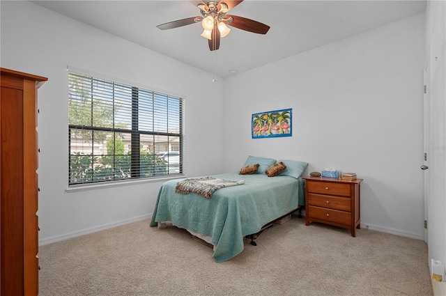 bedroom featuring light carpet, ceiling fan, and multiple windows