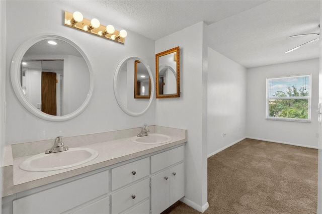 bathroom with ceiling fan, vanity, and a textured ceiling