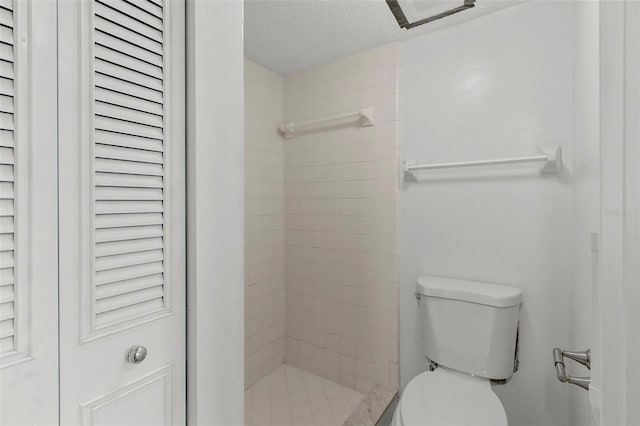 bathroom with tiled shower, a textured ceiling, and toilet