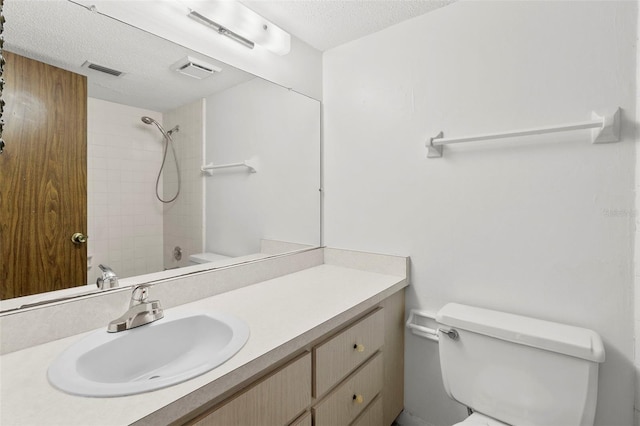 full bathroom featuring vanity, toilet, a textured ceiling, and tiled shower / bath