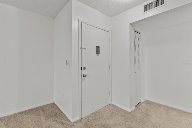 entryway with light colored carpet and a textured ceiling