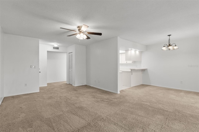 unfurnished living room featuring a textured ceiling, ceiling fan with notable chandelier, and light colored carpet