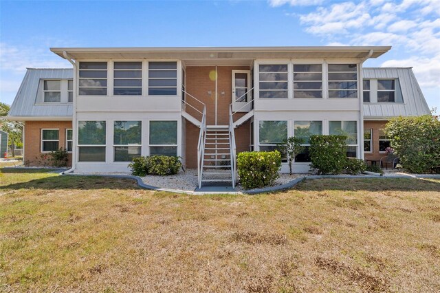 rear view of house with a sunroom and a yard