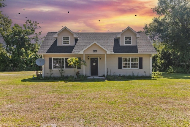 cape cod-style house featuring a lawn