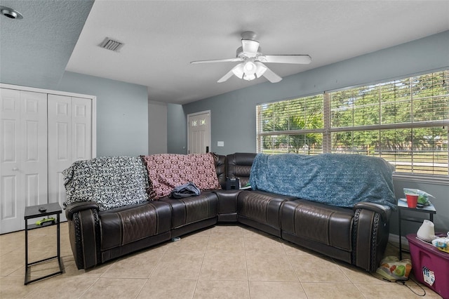 living room with light tile patterned floors, a textured ceiling, and ceiling fan