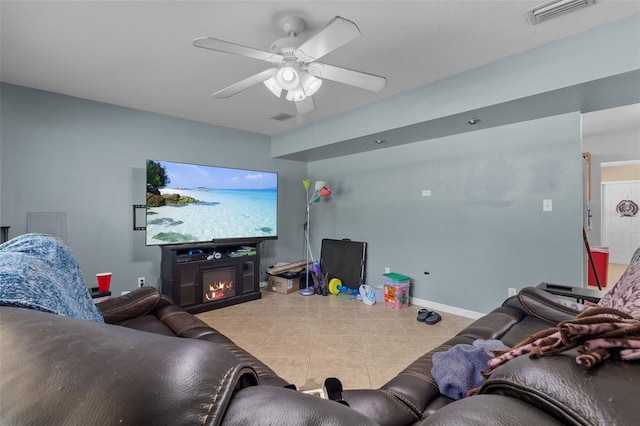 tiled living room with ceiling fan and a fireplace