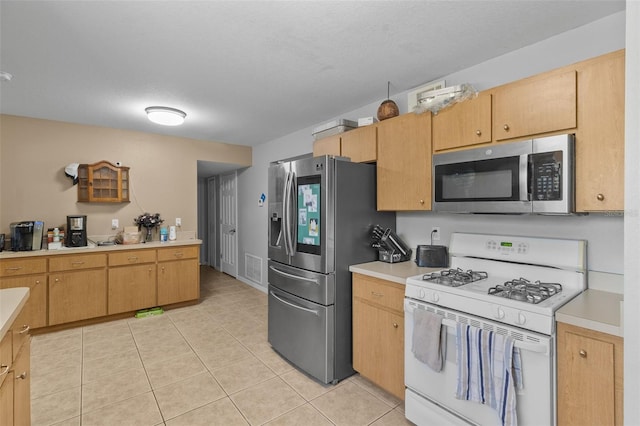 kitchen with light tile patterned floors, a textured ceiling, and appliances with stainless steel finishes