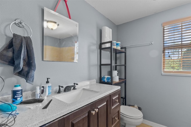 bathroom featuring plenty of natural light, vanity, and toilet