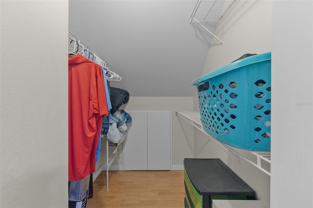 walk in closet featuring light hardwood / wood-style flooring and vaulted ceiling