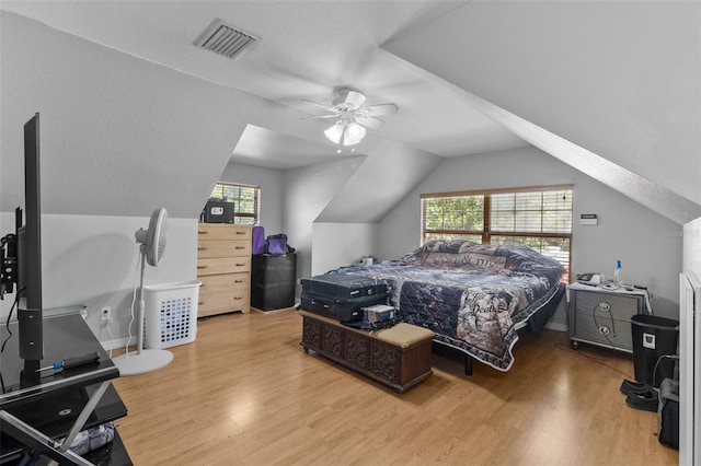 bedroom with ceiling fan, light wood-type flooring, a textured ceiling, and vaulted ceiling