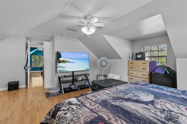 bedroom featuring ceiling fan, light hardwood / wood-style flooring, a textured ceiling, and vaulted ceiling