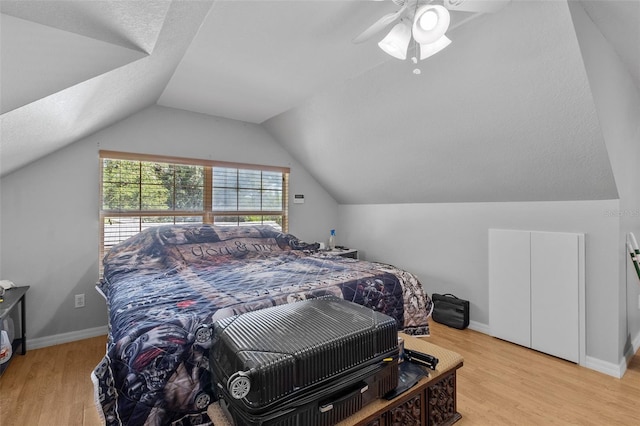 bedroom with a textured ceiling, light wood-type flooring, ceiling fan, and lofted ceiling