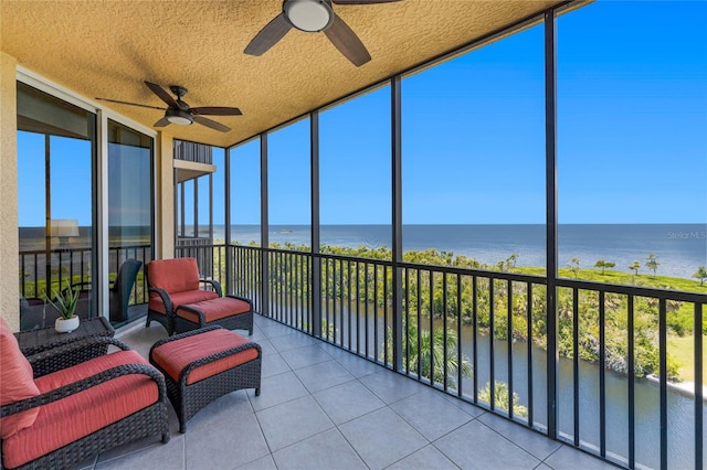 sunroom featuring ceiling fan, a wealth of natural light, and a water view