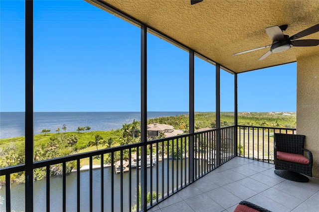 unfurnished sunroom featuring ceiling fan and a water view