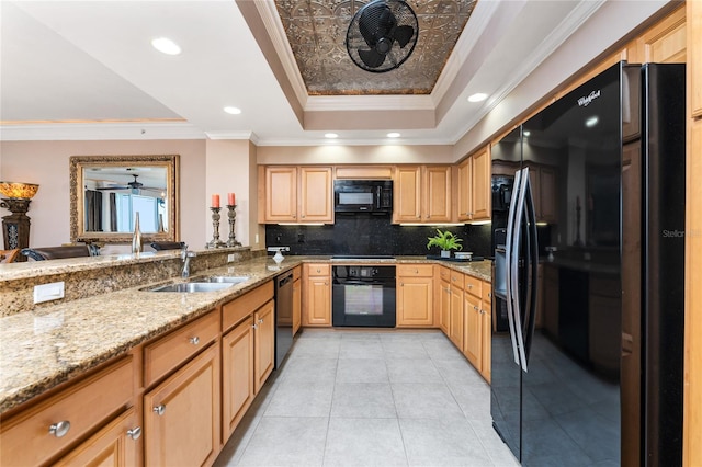 kitchen with light stone counters, black appliances, a tray ceiling, ornamental molding, and sink