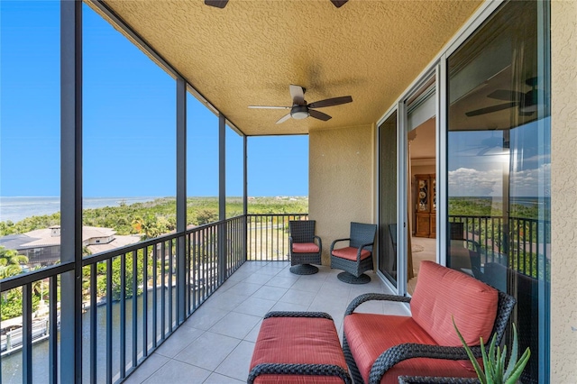 sunroom / solarium with plenty of natural light, ceiling fan, and a water view