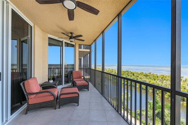 sunroom with ceiling fan and a water view