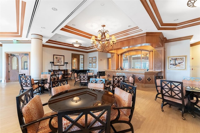 dining room featuring an inviting chandelier, decorative columns, a tray ceiling, ornamental molding, and light wood-type flooring