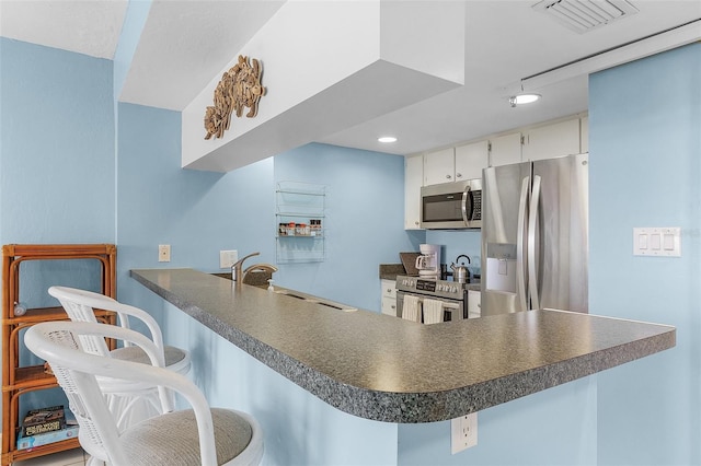 kitchen featuring white cabinets, a kitchen breakfast bar, sink, appliances with stainless steel finishes, and kitchen peninsula