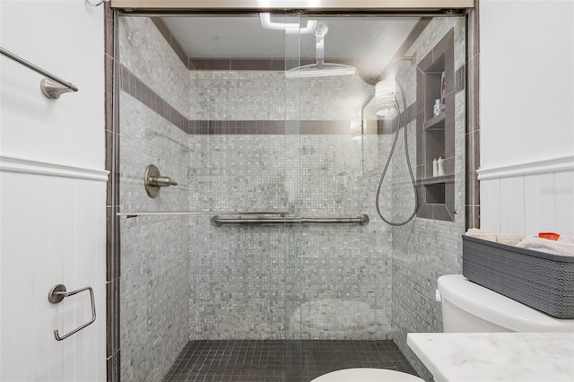 bathroom featuring toilet and a shower with door