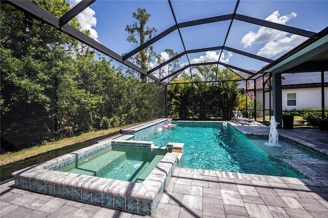 view of pool with glass enclosure, a patio area, pool water feature, and an in ground hot tub