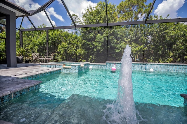 view of pool with glass enclosure, pool water feature, and an in ground hot tub