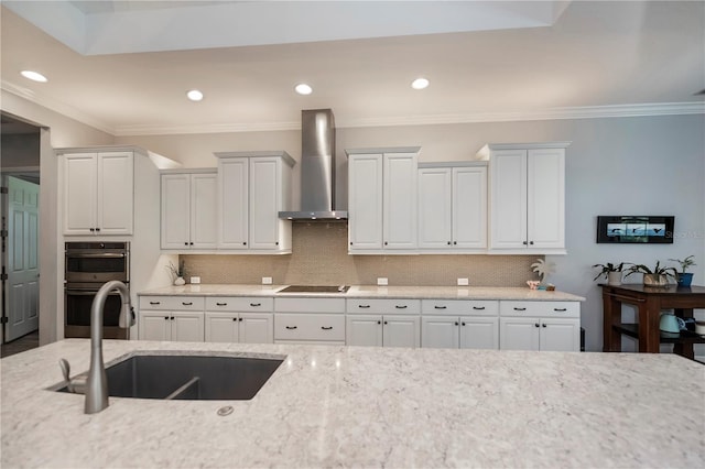 kitchen featuring backsplash, stainless steel double oven, wall chimney exhaust hood, and white cabinets