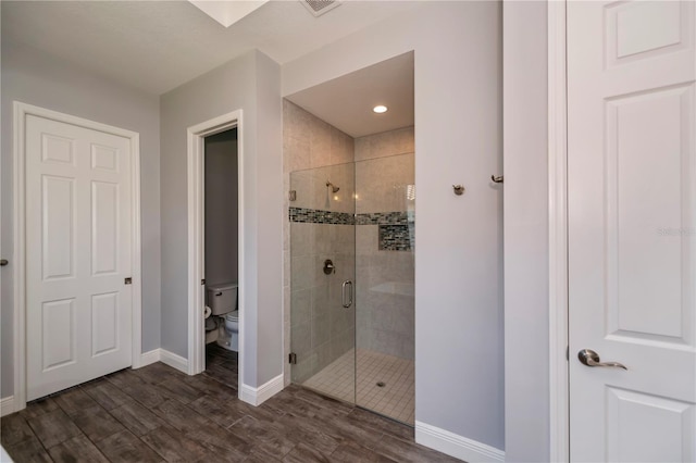 bathroom featuring wood-type flooring, toilet, and a shower with shower door