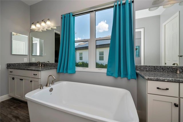 bathroom with hardwood / wood-style flooring, vanity, and a tub to relax in