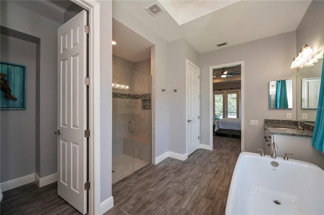 bathroom featuring wood-type flooring, ceiling fan, vanity, and plus walk in shower