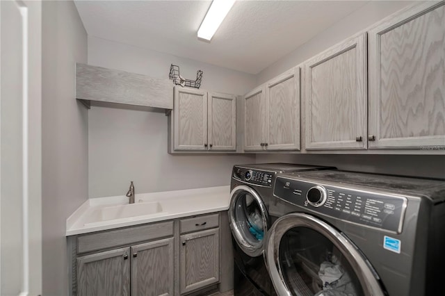 laundry area featuring cabinets, washer and dryer, a textured ceiling, and sink