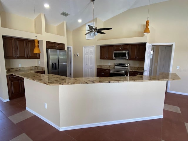 kitchen with light stone countertops, decorative light fixtures, high vaulted ceiling, and appliances with stainless steel finishes