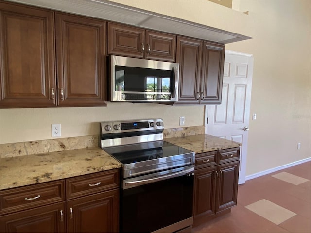 kitchen with light stone countertops, dark brown cabinetry, and stainless steel appliances