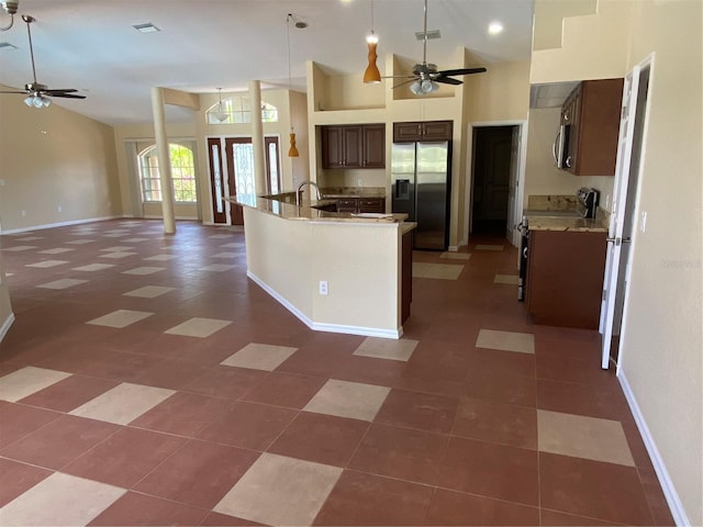 kitchen with ceiling fan, a high ceiling, dark brown cabinetry, and stainless steel appliances