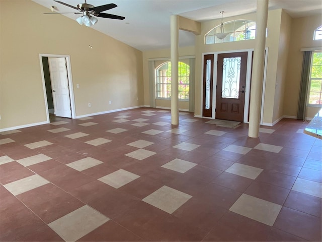 entryway with decorative columns, high vaulted ceiling, and ceiling fan