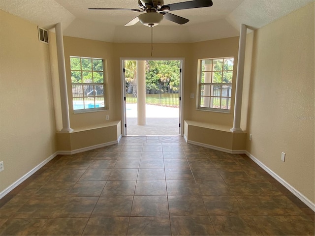 entryway with ceiling fan, dark tile patterned floors, a textured ceiling, decorative columns, and vaulted ceiling