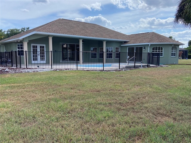 rear view of house with a patio area, a fenced in pool, a yard, and french doors