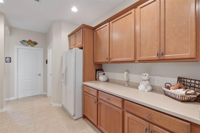 kitchen featuring white fridge with ice dispenser and light tile patterned flooring