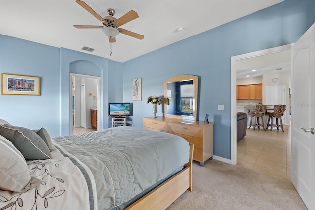 bedroom with connected bathroom, ceiling fan, and light carpet