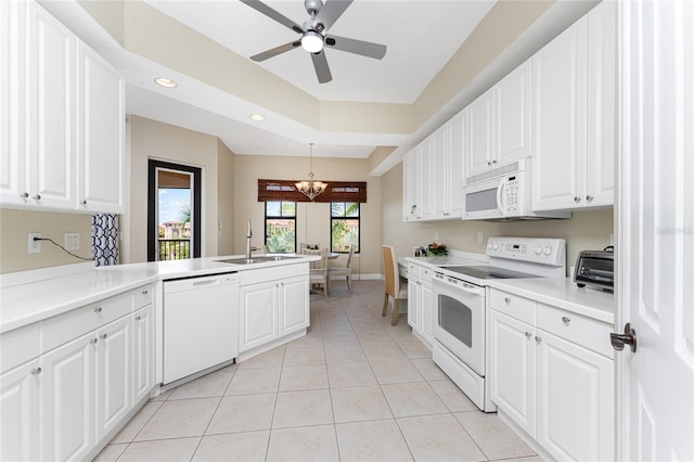 kitchen with white appliances, sink, kitchen peninsula, light tile patterned flooring, and white cabinetry