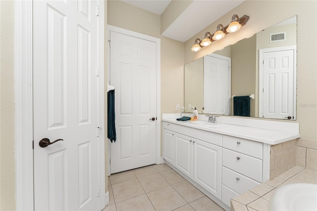 bathroom with tile patterned flooring, vanity, and a relaxing tiled tub