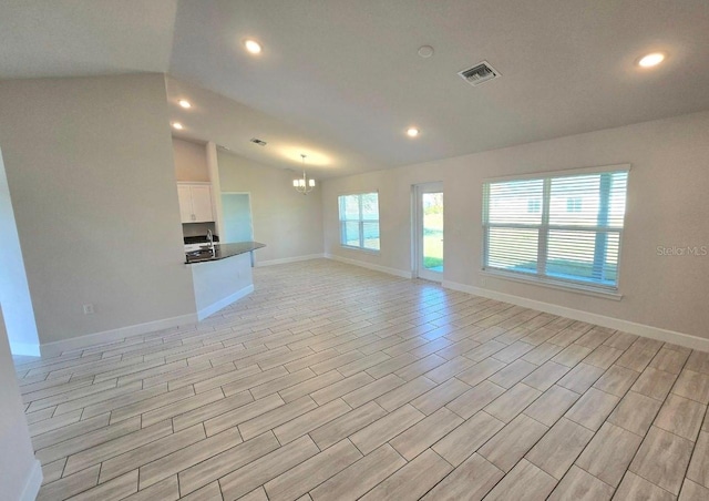 unfurnished living room featuring lofted ceiling and an inviting chandelier