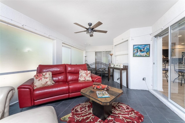 living room featuring ceiling fan and dark tile patterned flooring