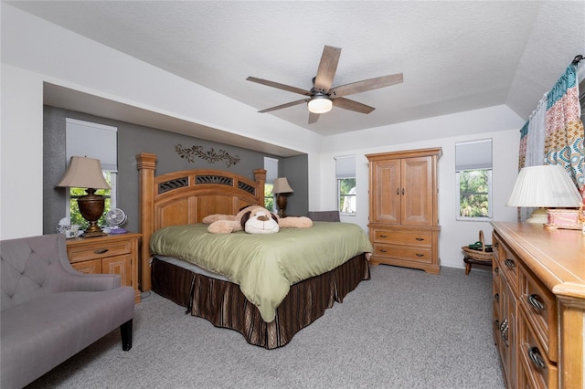 bedroom with multiple windows, light colored carpet, a textured ceiling, and ceiling fan