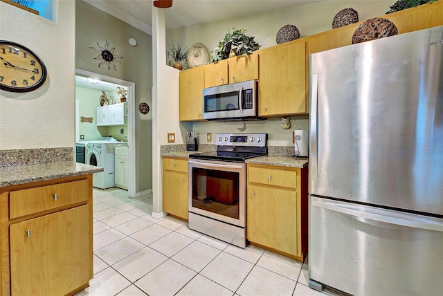 kitchen with washer and clothes dryer, light stone countertops, stainless steel appliances, and light tile patterned floors