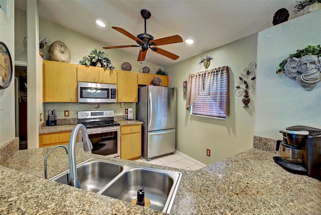 kitchen featuring ceiling fan, sink, stainless steel appliances, vaulted ceiling, and light tile patterned floors